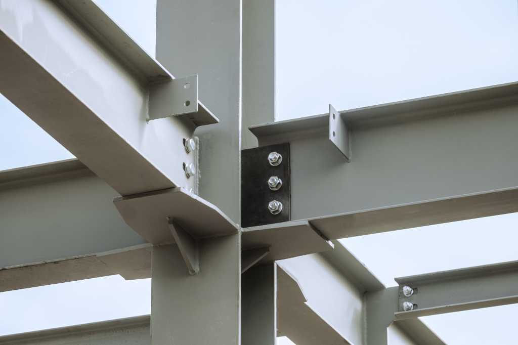 Steel joints. Mounting bolted connection of steel beams before welding. Metal construction covered protective gray primer. Close-up.